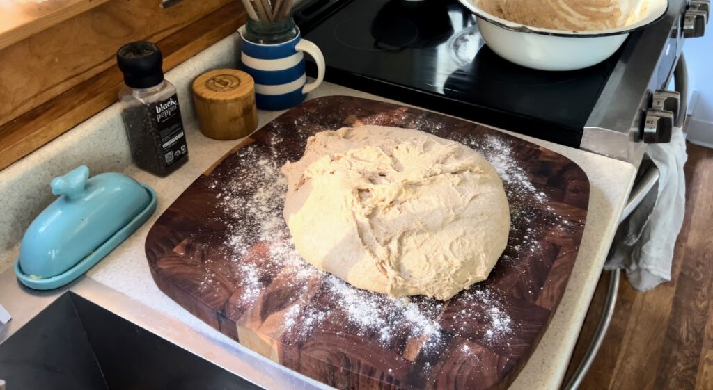 Whole wheat sourdough dough on a floured wooden cutting board.