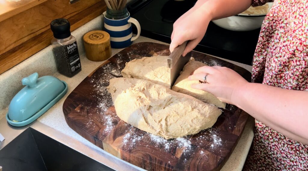 Cutting sourdough dough with a pastry scraper.