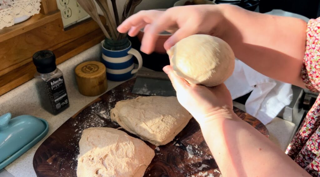 Shaping sourdough into a round loaf.