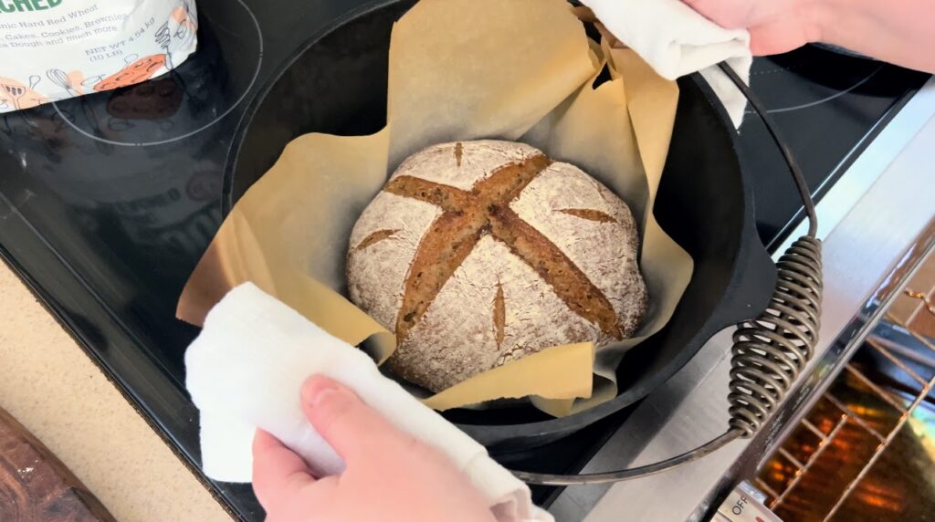 Freshly baked, hearty whole wheat sourdough bread in a cast iron dutch oven.