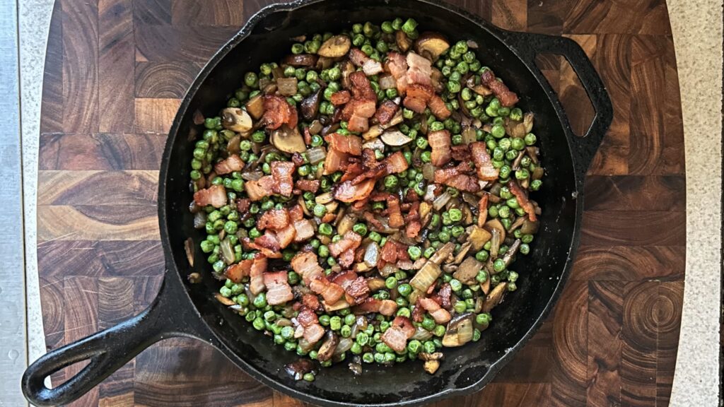 Bacon and peas with mushrooms and onions in a cast iron skillet for an easy one pan meal.