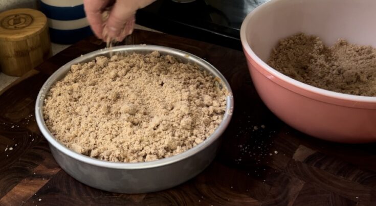 Streusel crumb topping on top of pumpkin coffee cake next to a pink vintage pyrex bowl.