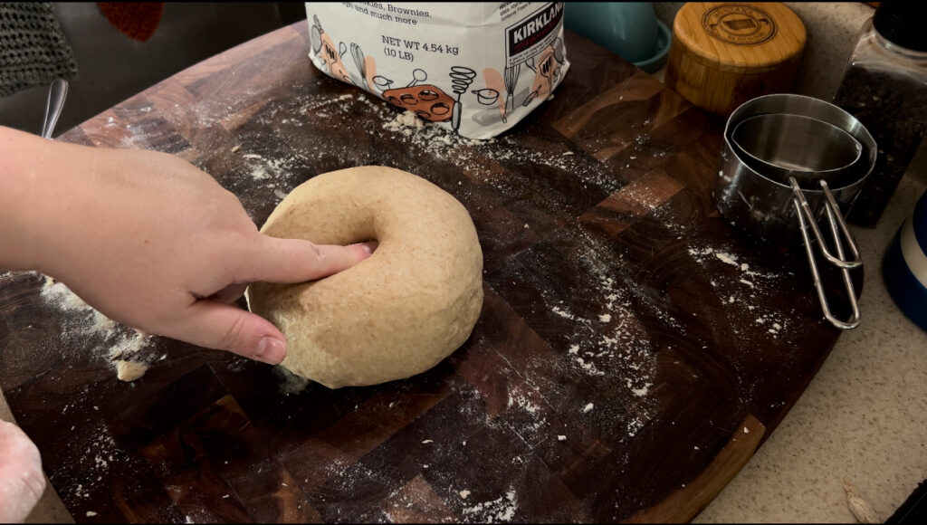 Pressing finger into honey whole wheat bread dough to make sure it has been kneaded enough.