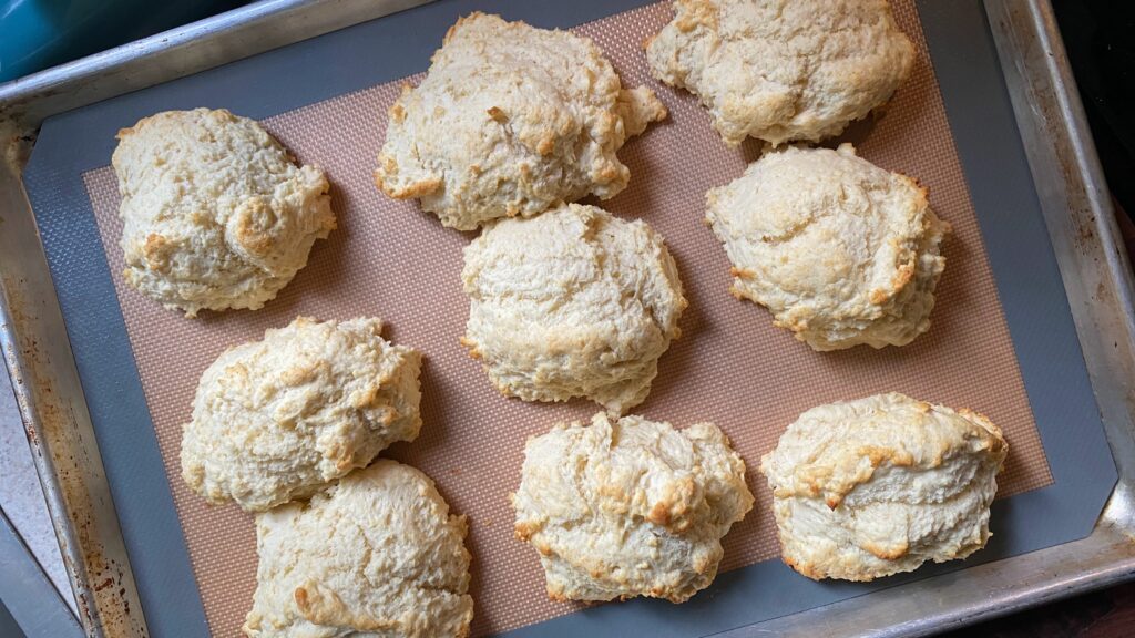 Freshly baked easy drop biscuits on a baking sheet lined with a silicone mat.