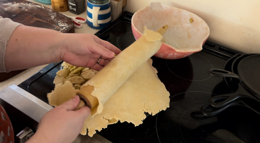 Rolling our pie crust dough onto the top of an apple pie.