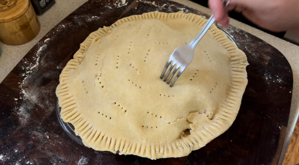 Piercing the top of a pie crust with a fork for letting steam out during baking. 