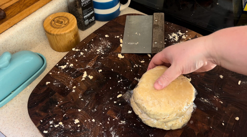 Two round disks of all butter pie crust dough wrapped in plastic wrap for chilling in the fridge.