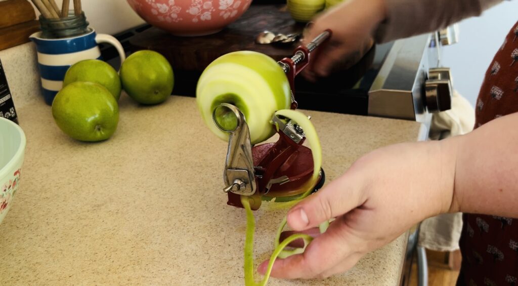 Peeling granny smith apples with a red apple peeler that peels and cores apples.