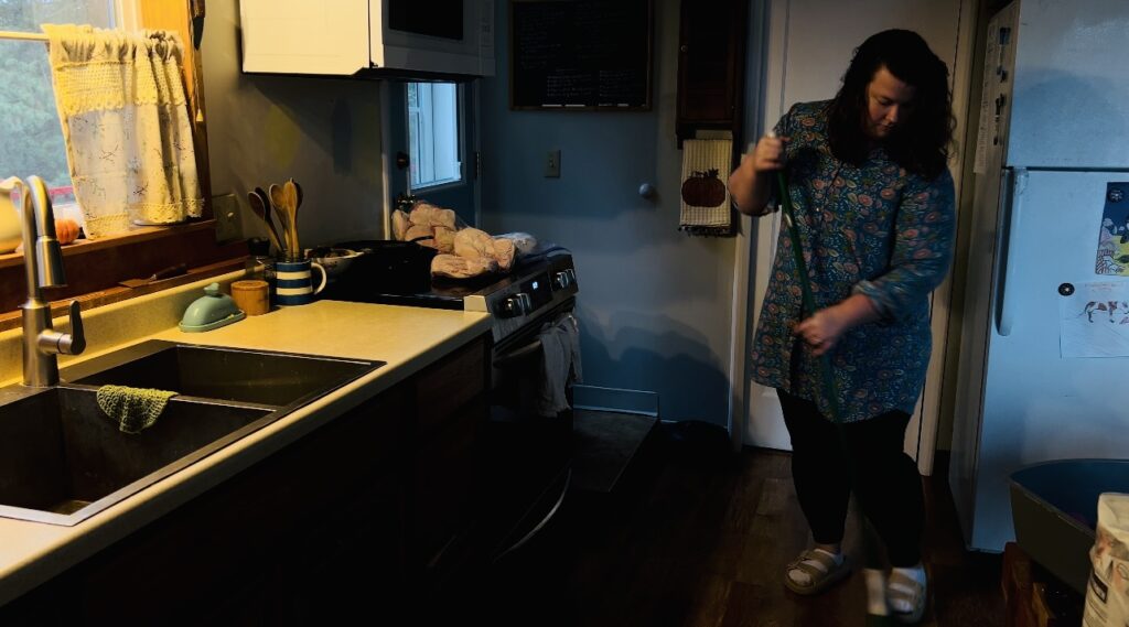 Woman sweeping her kitchen floor.