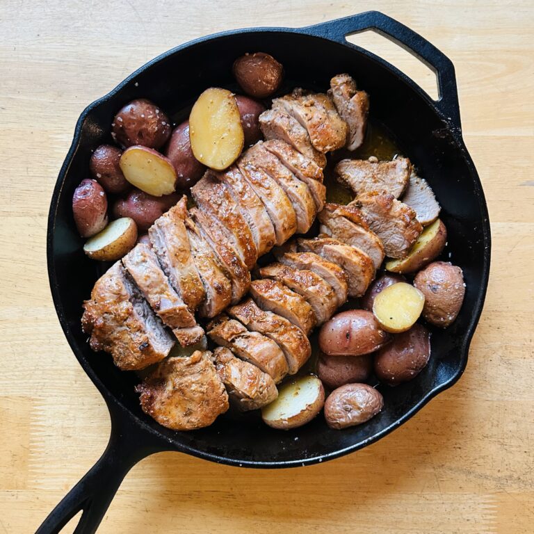 Easy roasted pork tenderloin and potatoes roasted in a large cast iron skillet.