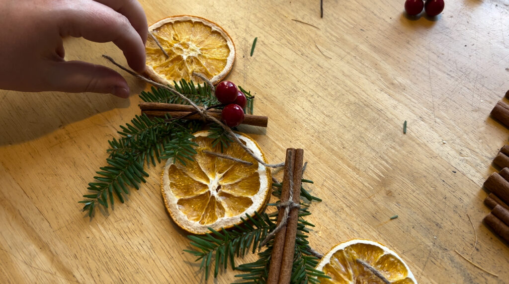 Christmas garland made with dehydrated orange slices, cinnamon  sticks, hemlock springs and fake red berries.