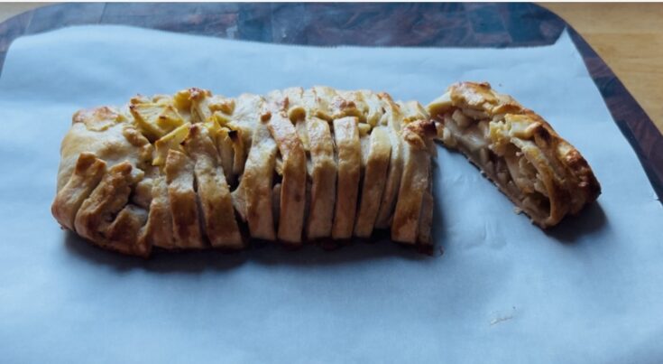 Freshly baked apple strudel cut open to show the apple filling.