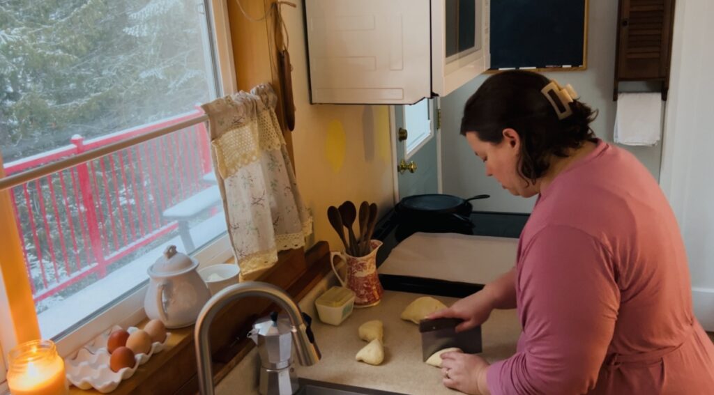 Woman cutting sourdough bagel dough into pieces for shaping into bagels.