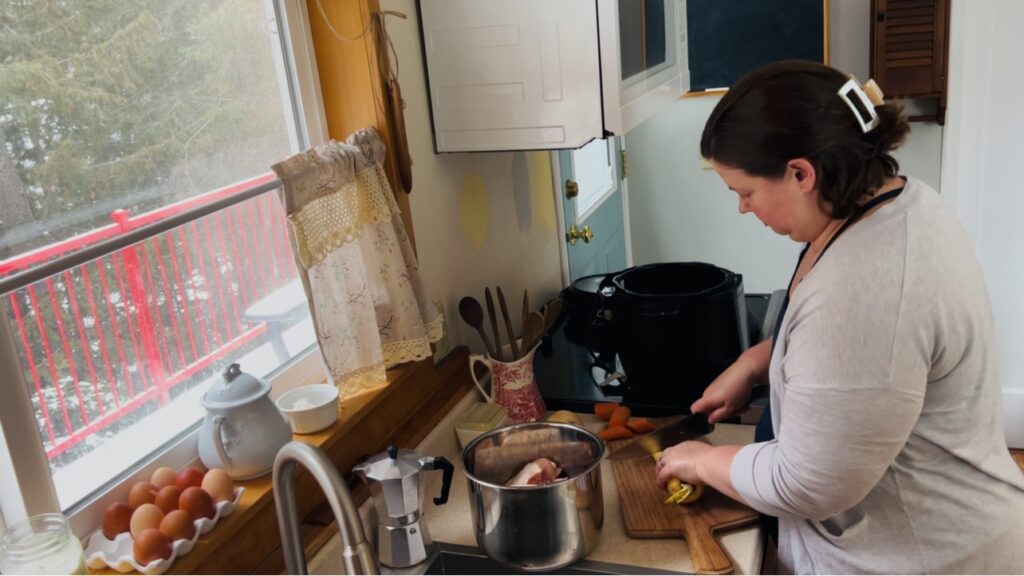 Woman chopping vegetables at her kitchen counter for making homemade chicken broth. 