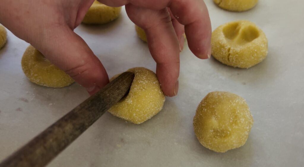 Pressing the heart shape into strawberry thumbprint cookies.