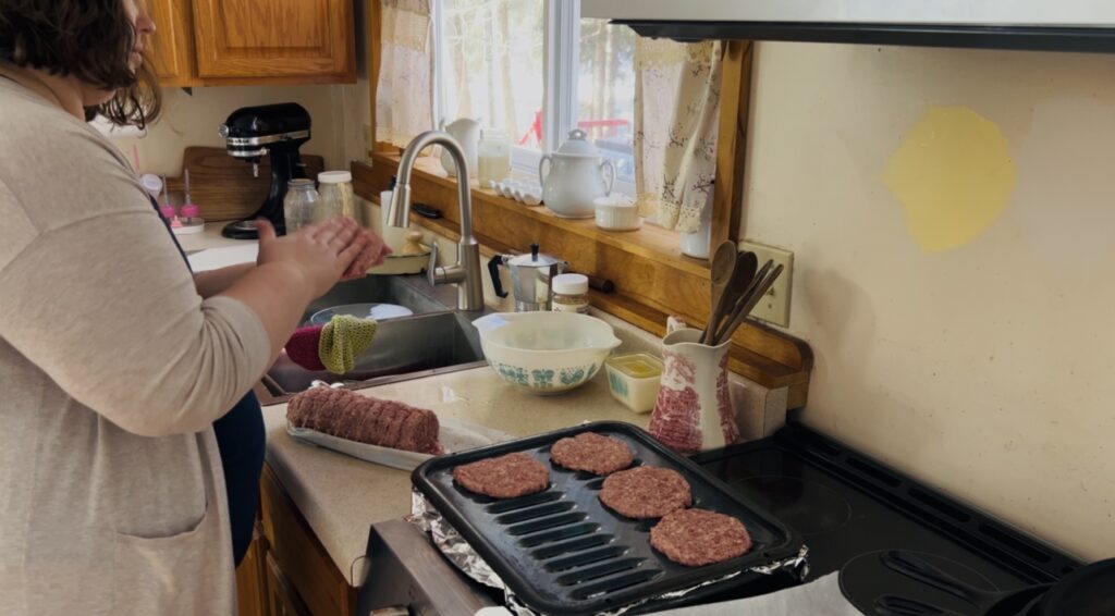 Preparing sausage patties and placing on a broiler pan for cooking in the oven.