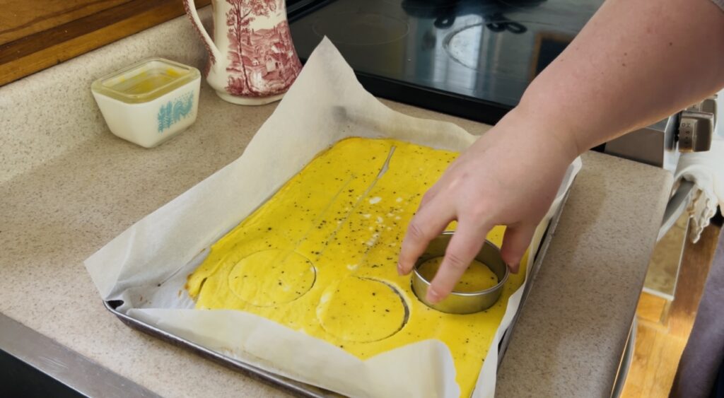 Cutting out cooked scrambled eggs for breakfast sandwiches.