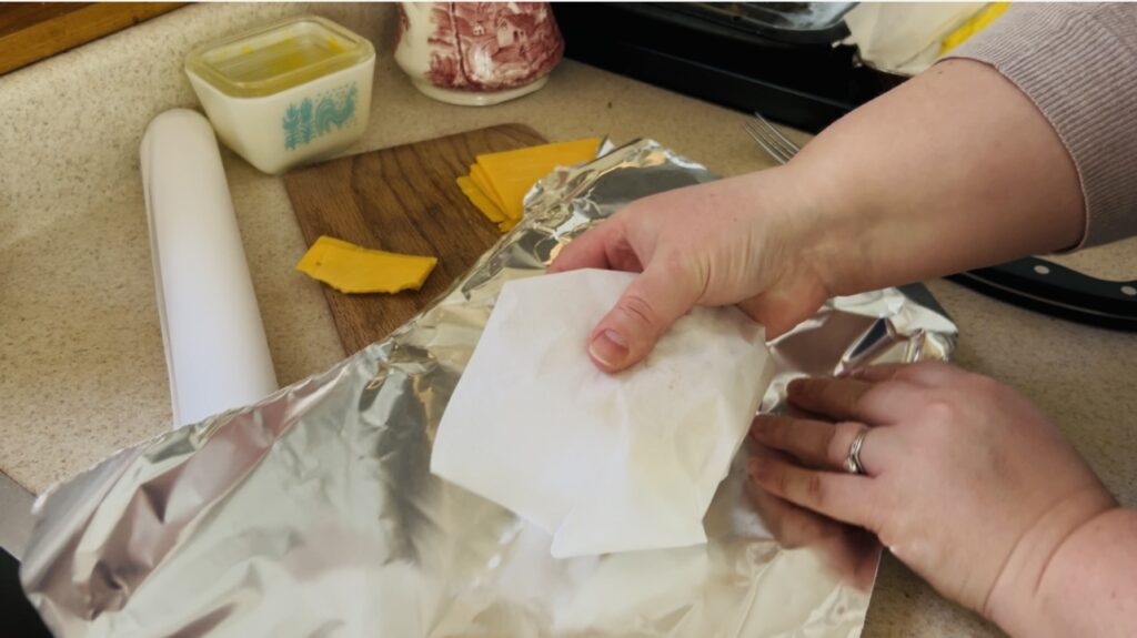 Wrapping a breakfast sandwich wrapped in parchment in foil.