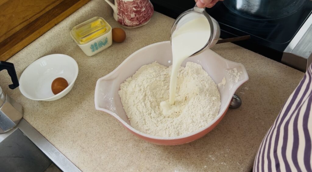 Pouring milk into a butter and flour mixture for scone dough.