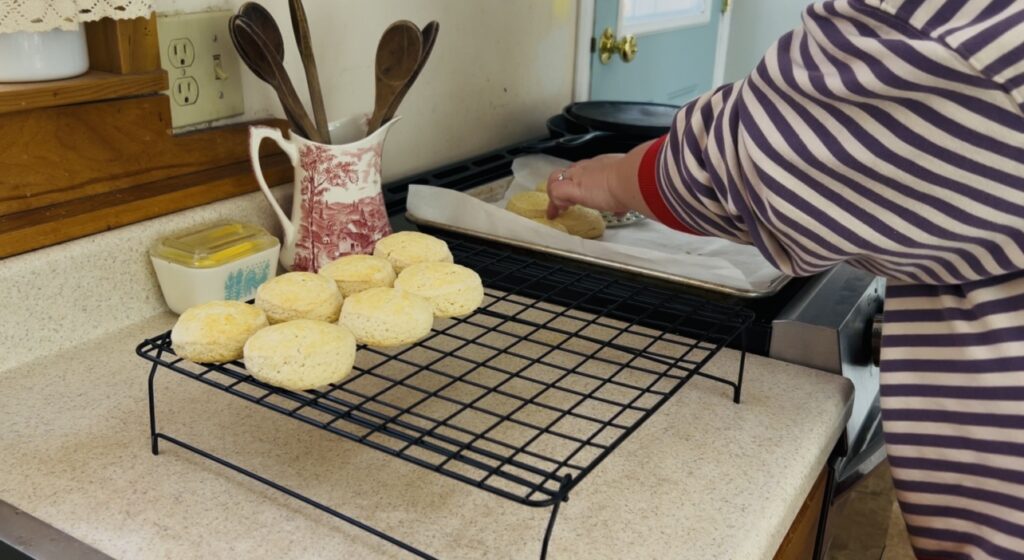 Placing freshly baked classic scones onto a wire rack to cool.