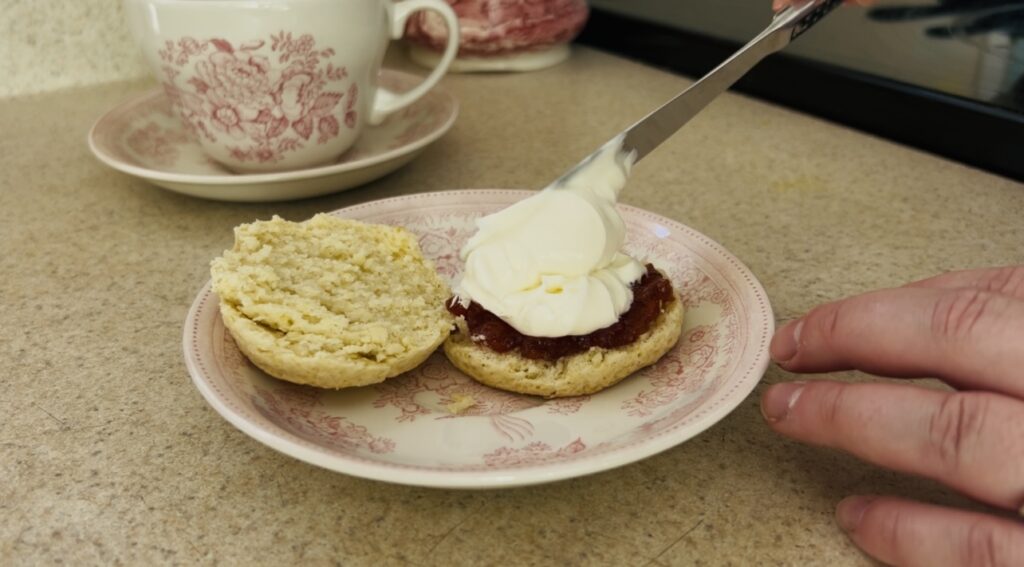 Spreading clotted cream onto freshly baked classic scones.