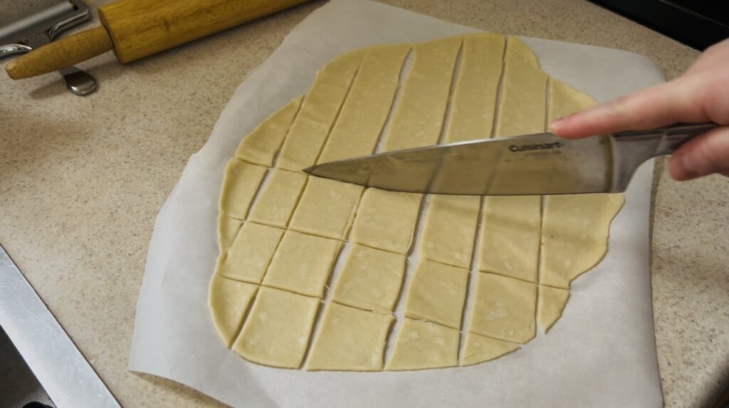 Cutting cracker dough with a knife.