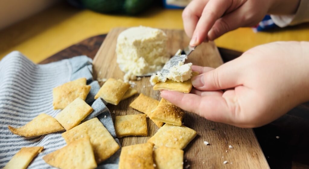 Spreading a homemade cracker with a soft herbed cheese.