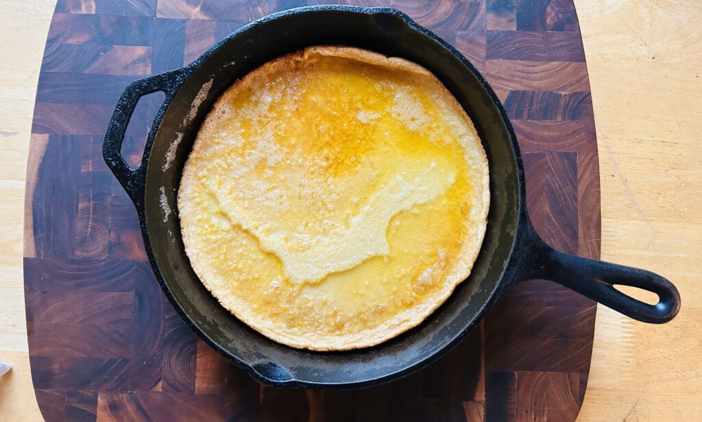 Freshly cooked Dutch baby pancake in a cast iron skillet.