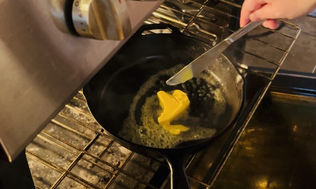 Melting butter in a hot preheated cast iron skillet for sourdough Dutch baby pancake.