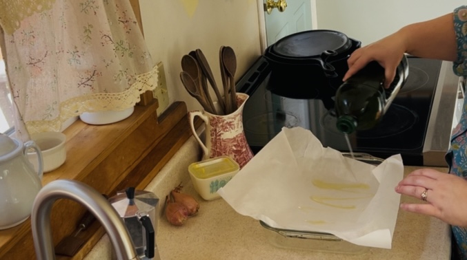 Pouring oil into a parchment lined baking pan for focaccia bread.