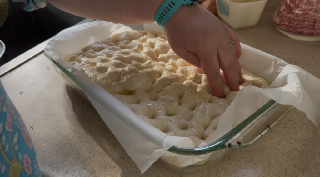 Pressing holes into focaccia dough.