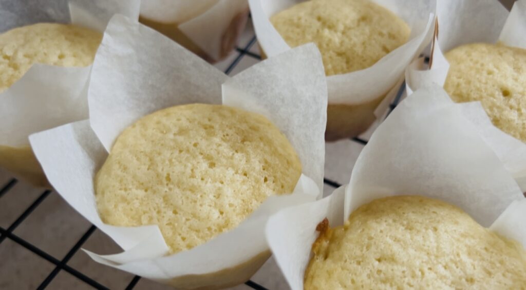 Freshly baked easy vanilla cupcakes cooling on a wire rack.