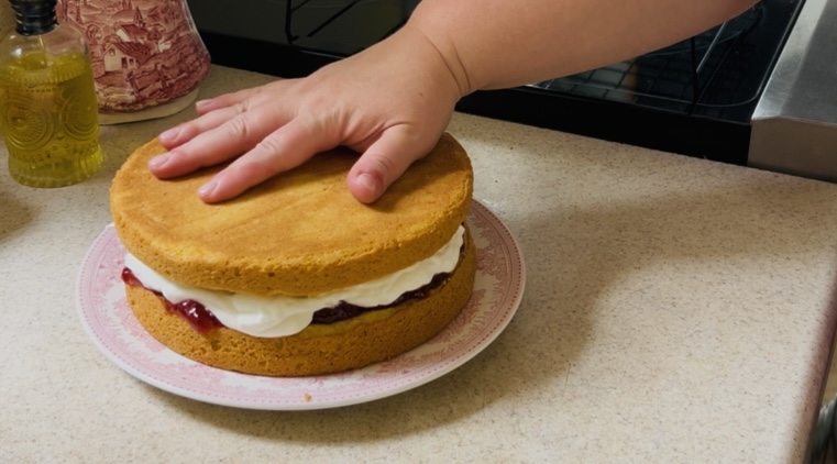 Placing the top layer on a round sponge cake.