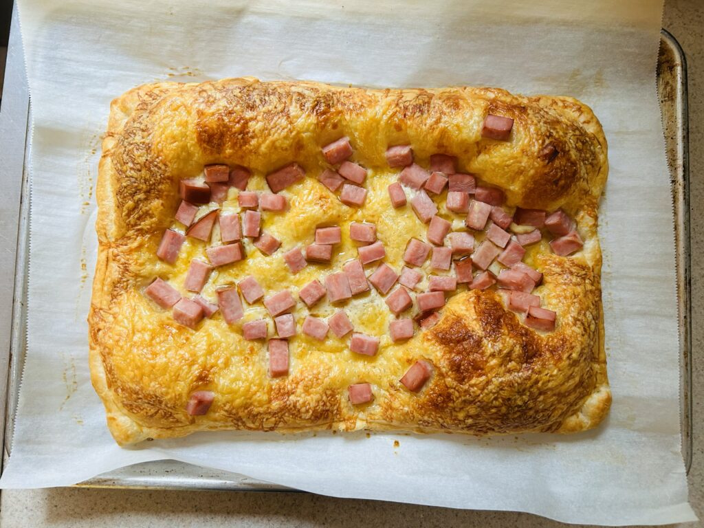 Golden, flaky puff pastry topped with cubes of ham and Swiss cheese, baked to golden perfection.